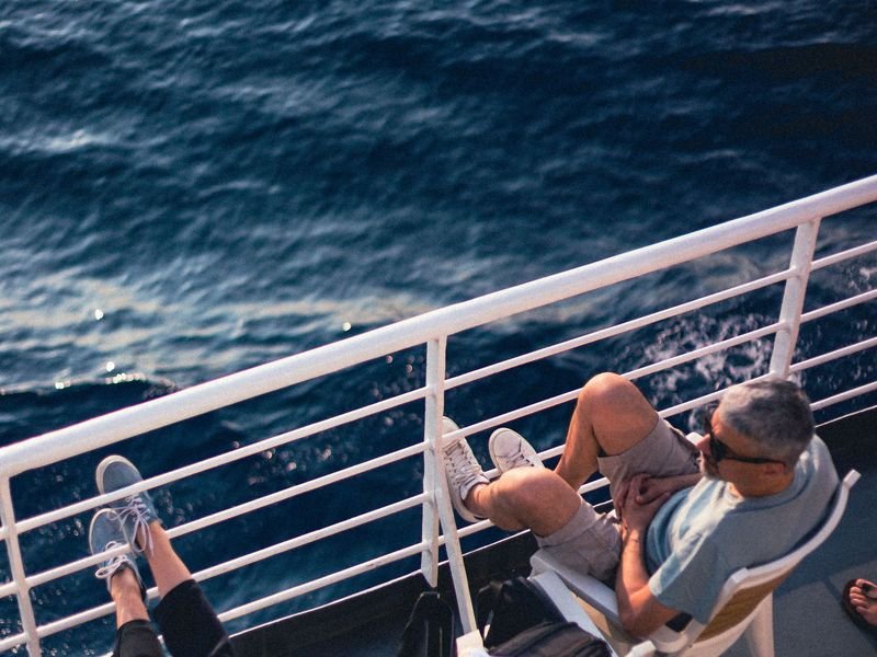 Two travellers relaxing on a ship deck by the sea
