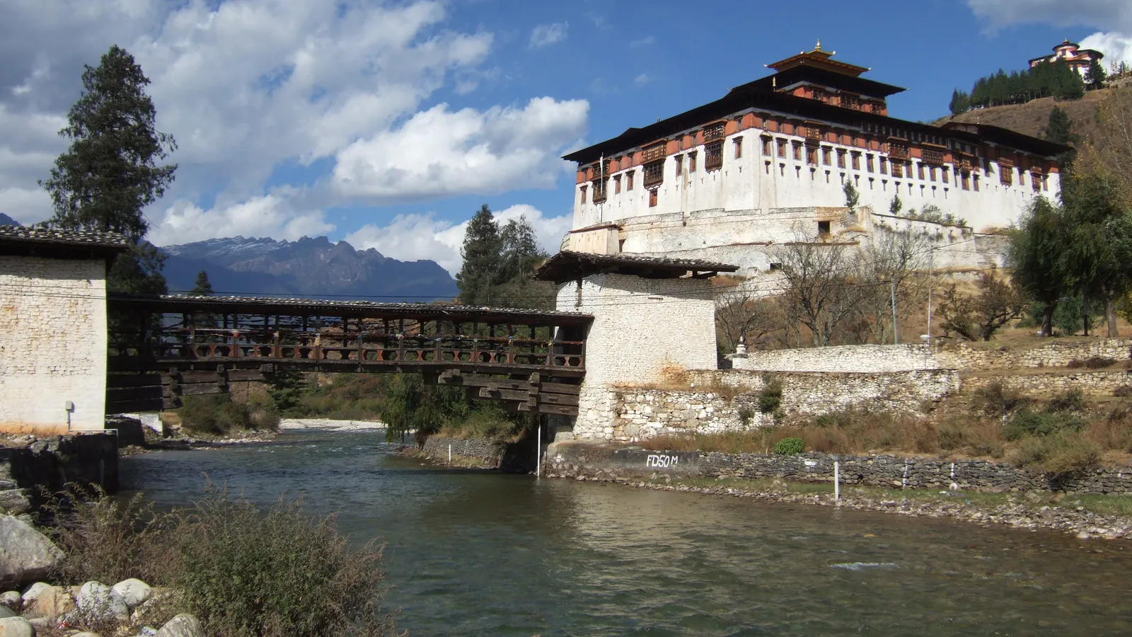 Rinpung Dzong and the traditional covered wooden bridge over the river in Paro