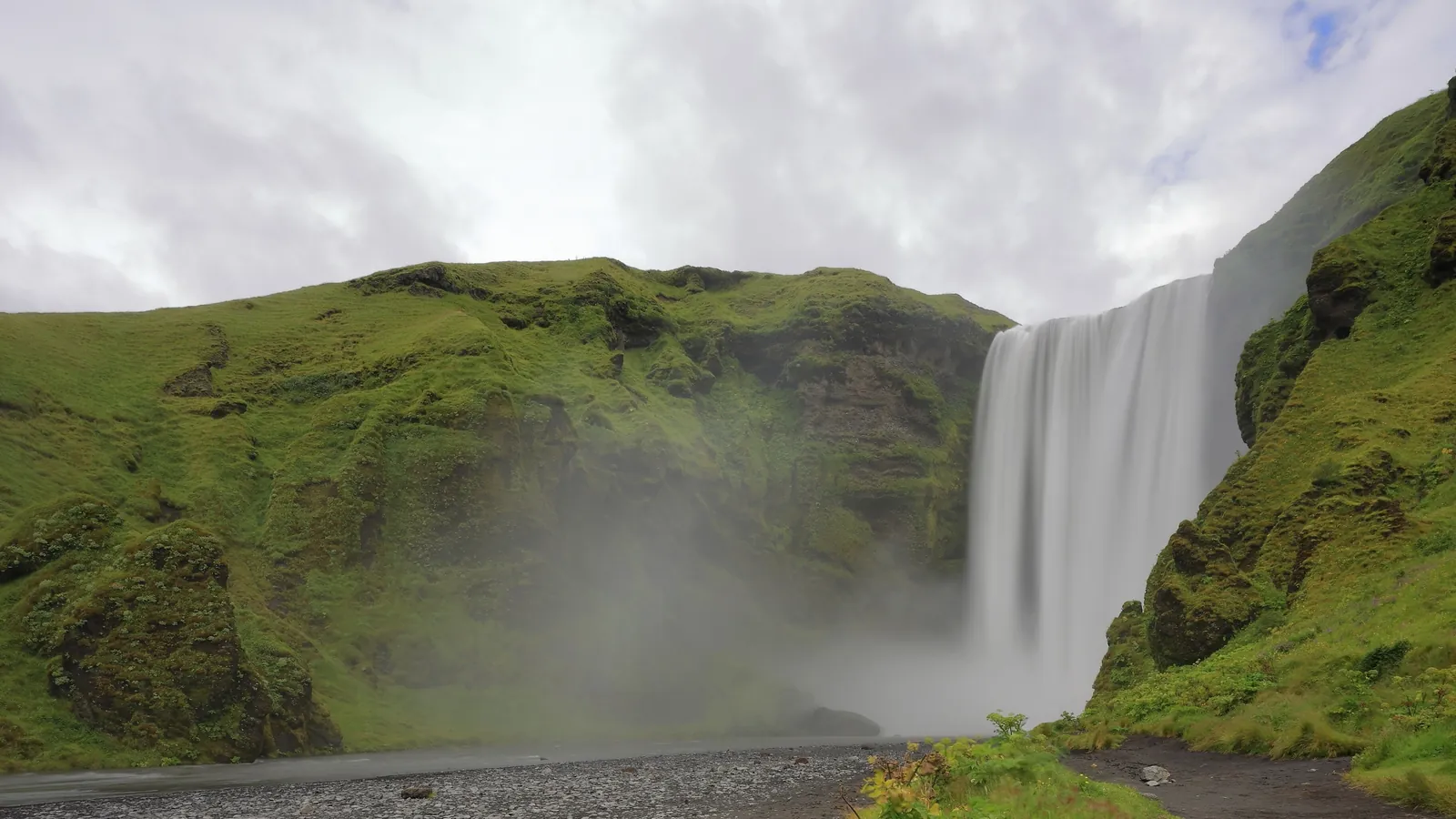 Skógafoss, a 60-metre waterfall on Iceland's South Coast, surrounded by green cliffs
