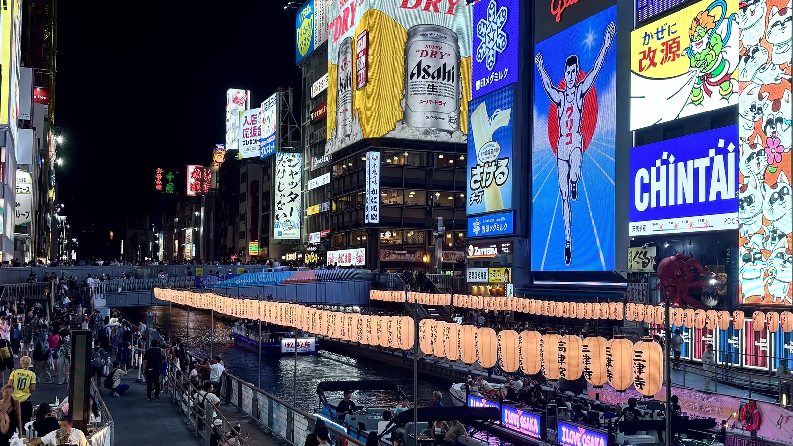 Neon signs and crowds along the Dotonbori canal in Osaka, the heart of the city's street food scene at night