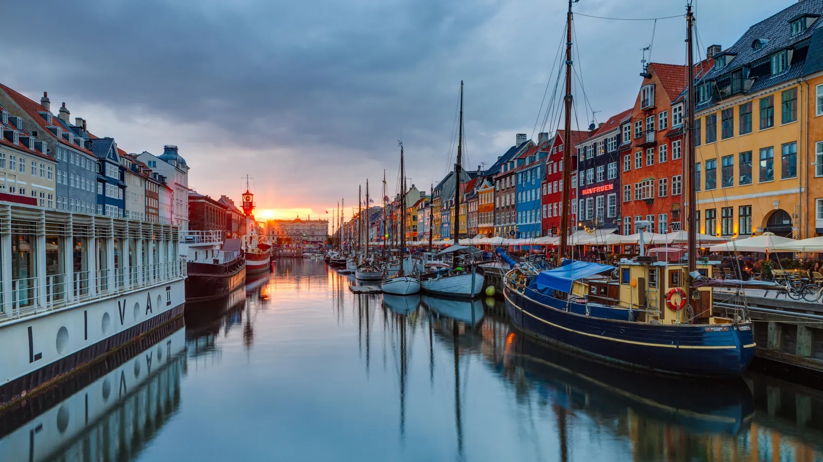 Colourful townhouses and wooden ships line the Nyhavn canal in Copenhagen at sunset