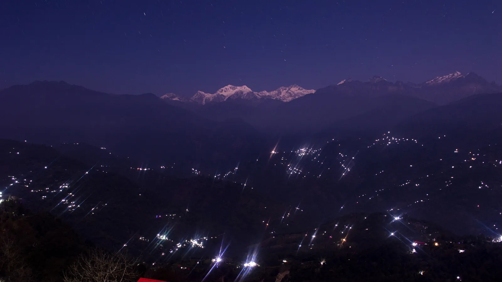 Kanchenjunga glows above the lights of hill towns in west Sikkim