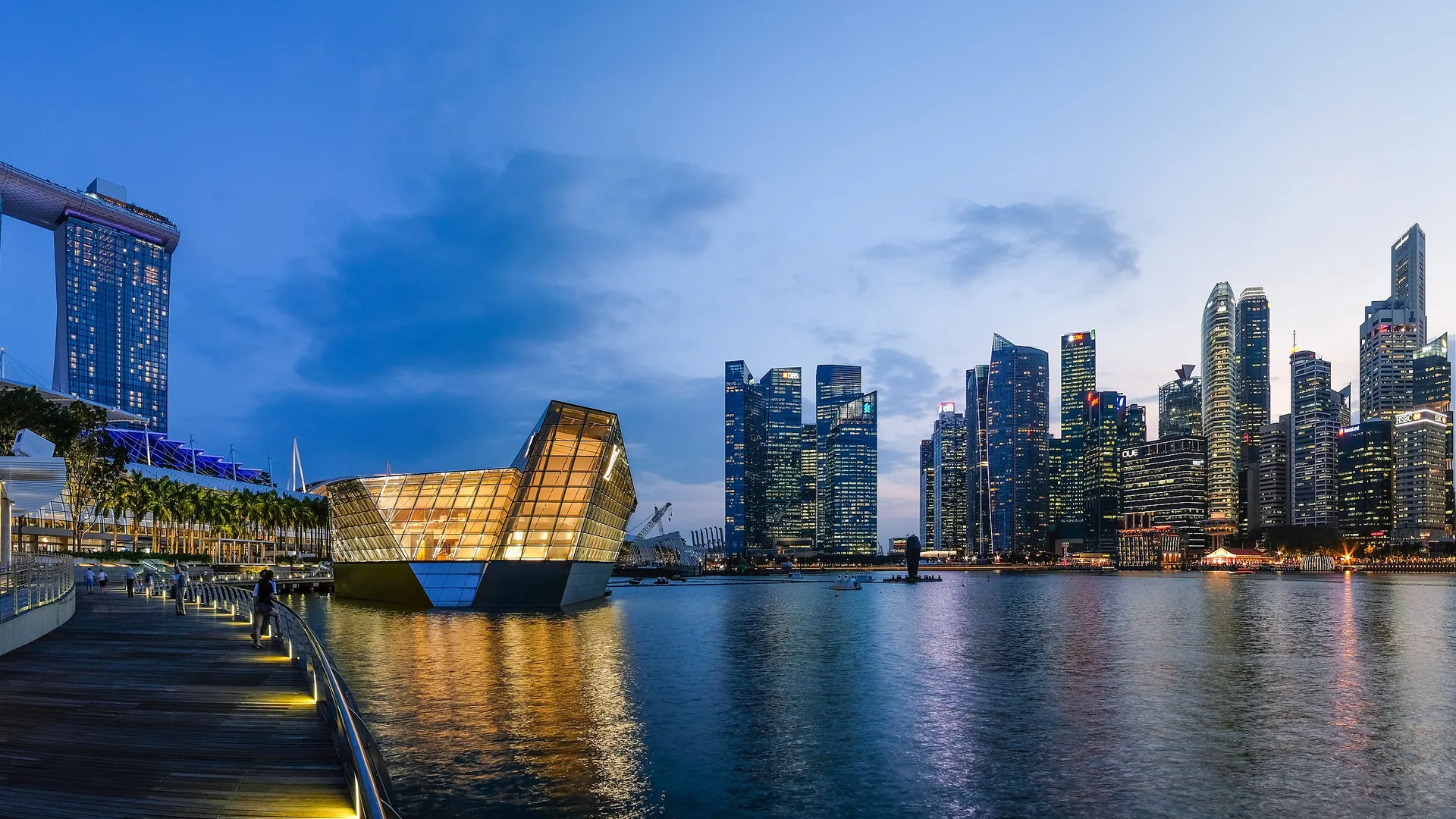 The skyline of Singapore's Marina Bay at night, with the lotus-shaped ArtScience Museum and city towers reflected in the water