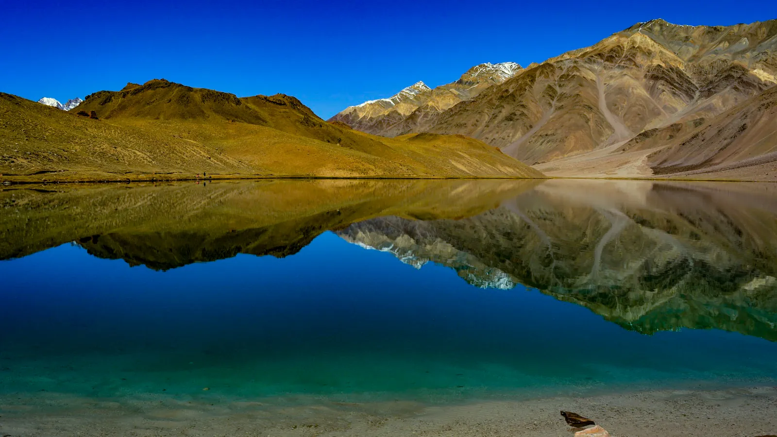 The still water of Chandratal lake reflecting the surrounding mountains
